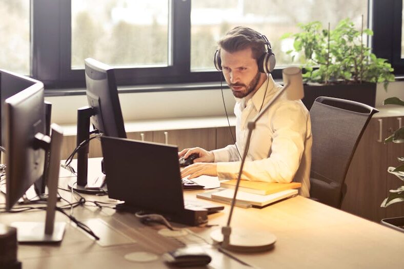 Man With Headphones Facing Computer Monitor